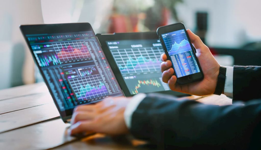 A forex broker doing LCG review on his smartphone and laptop